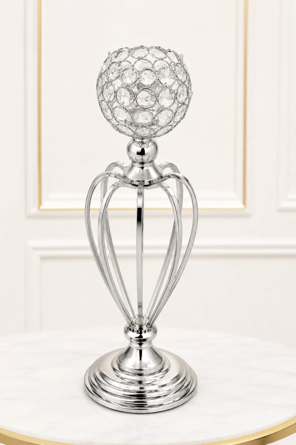 Luxury Silver Crystal Goblet Candle Holder – Elegant Hollow-Cage Pillar Centerpiece Elegant silver crystal goblet candle holder featuring an open hollow-cage metallic stem and a tiered circular base on a marble table surface.