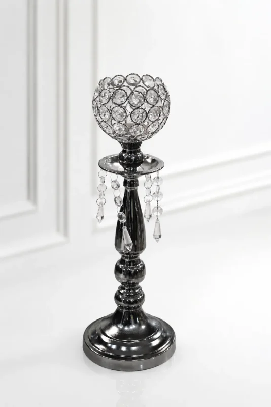 Glamorous gunmetal black crystal candle holder featuring a beaded crystal goblet, hanging crystal teardrop prisms, and a dark metallic tiered pedestal base on a glossy white surfac