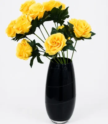 Tall black textured ceramic vase holding artificial purple flowers on a marble surface,