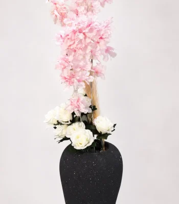 Speckled black vase with tall pink cherry blossoms and white roses on a white background