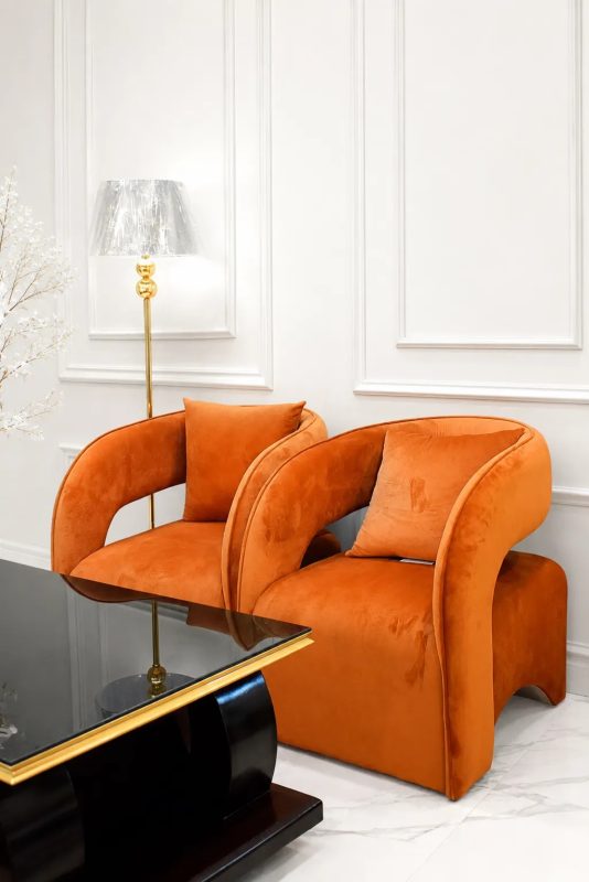 Modern orange velvet accent chair with curved contemporary design.